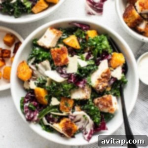 A bowl of crispy chicken kale caesar salad, fully dressed and ready to be served.