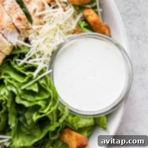 A bowl of creamy homemade Caesar dressing, garnished with fresh herbs.