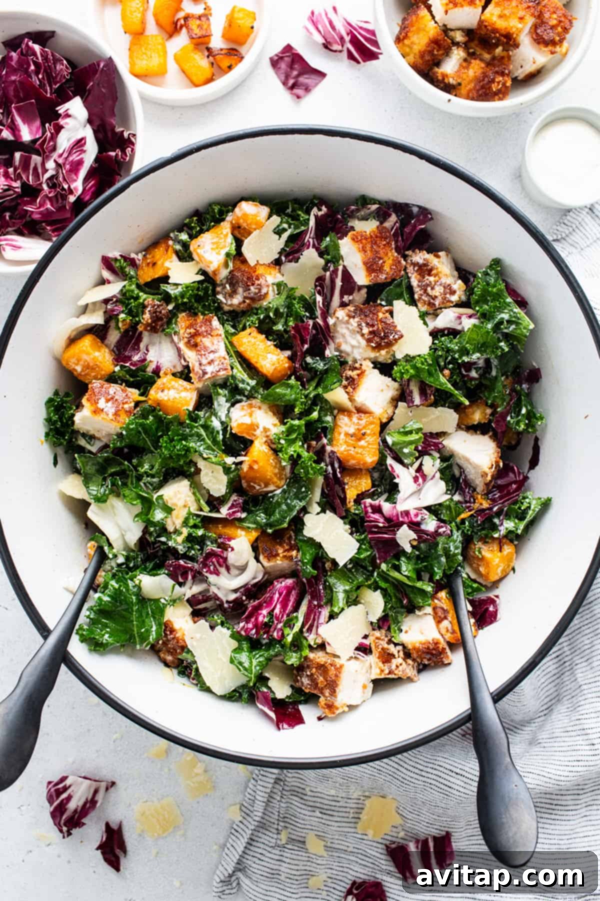 A full, vibrant bowl of crispy chicken kale caesar salad, showcasing the abundance of fresh ingredients.
