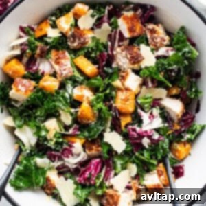 A bowl of kale salad with chicken and parmesan cheese, ready to be enjoyed.