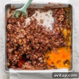 A baking pan containing unbaked chocolate banana oatmeal mixture, with a scoop removed to show the rich texture.