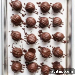 Chocolate truffles cooling on a baking sheet after being dipped.