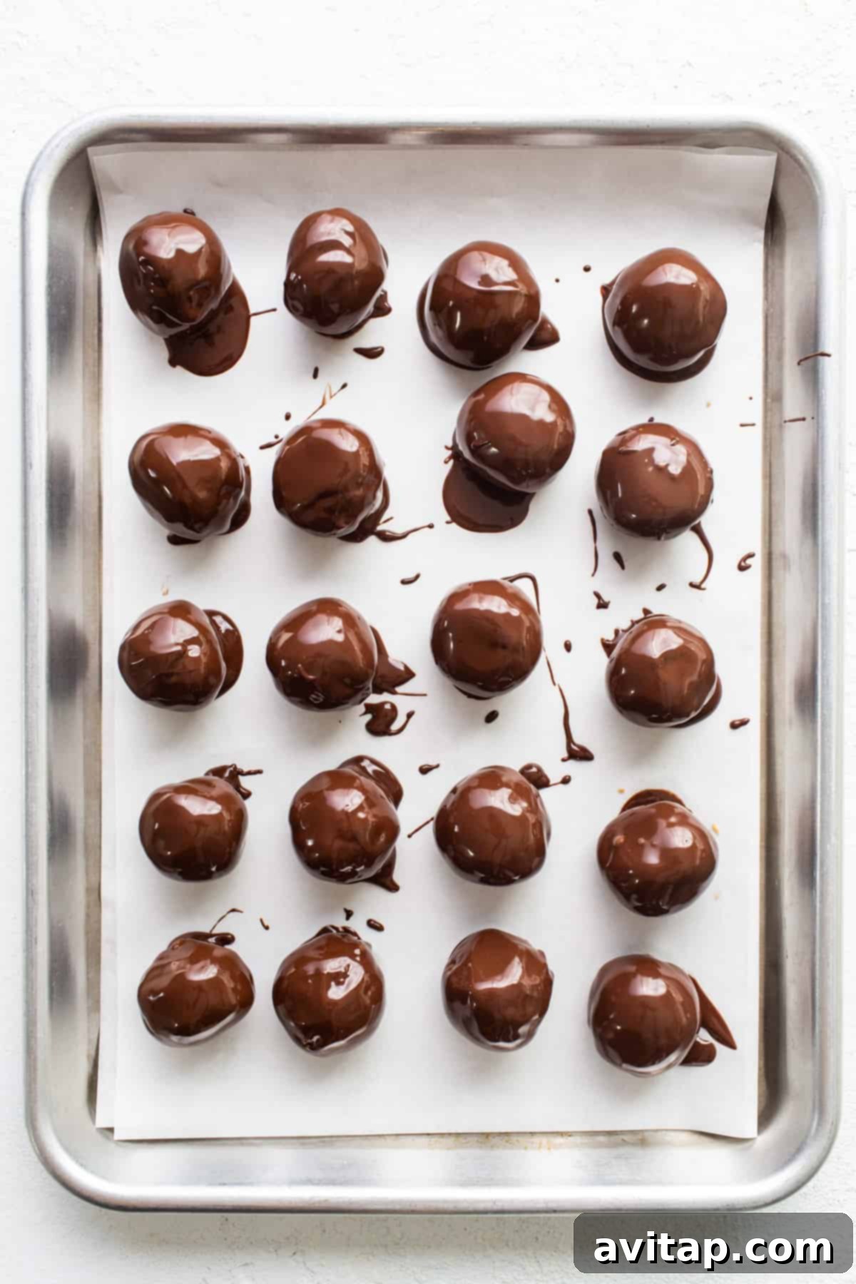 A tray of freshly coated chocolate truffles, garnished with crushed nuts, waiting to set.