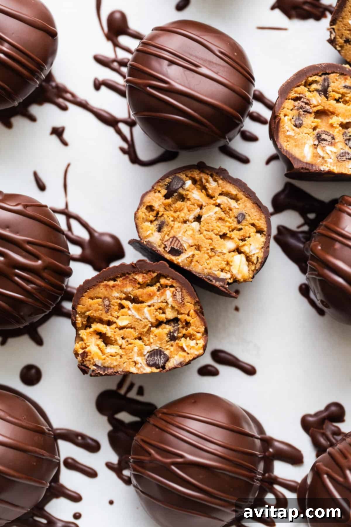 Chocolate-covered protein treats, possibly egg-shaped, on a white surface, signifying the versatile shapes these truffles can take.