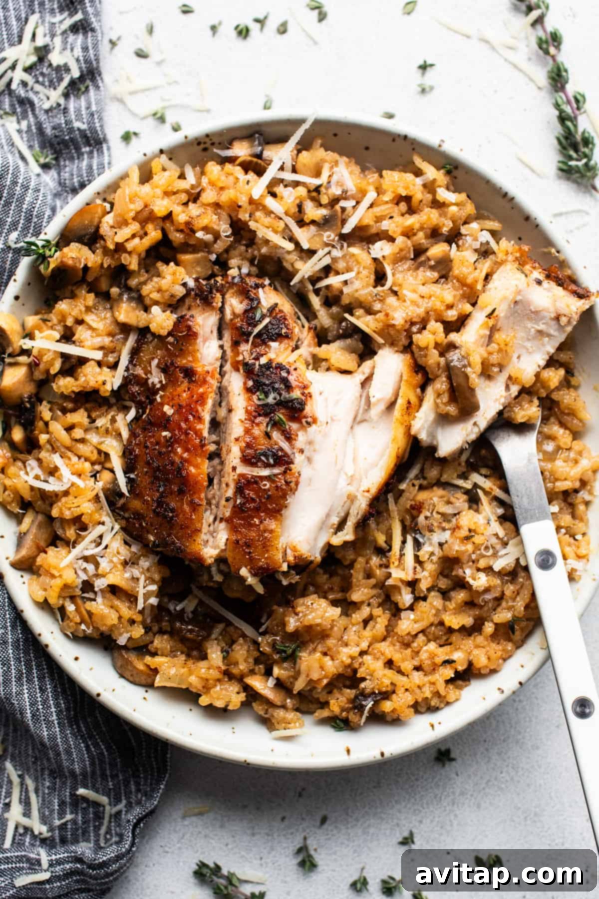 Chicken risotto with mushrooms and thyme on a plate, garnished with fresh herbs.