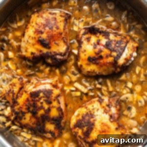 Chicken breasts arranged in a pan with mushrooms and tomatoes, covered with a lid.