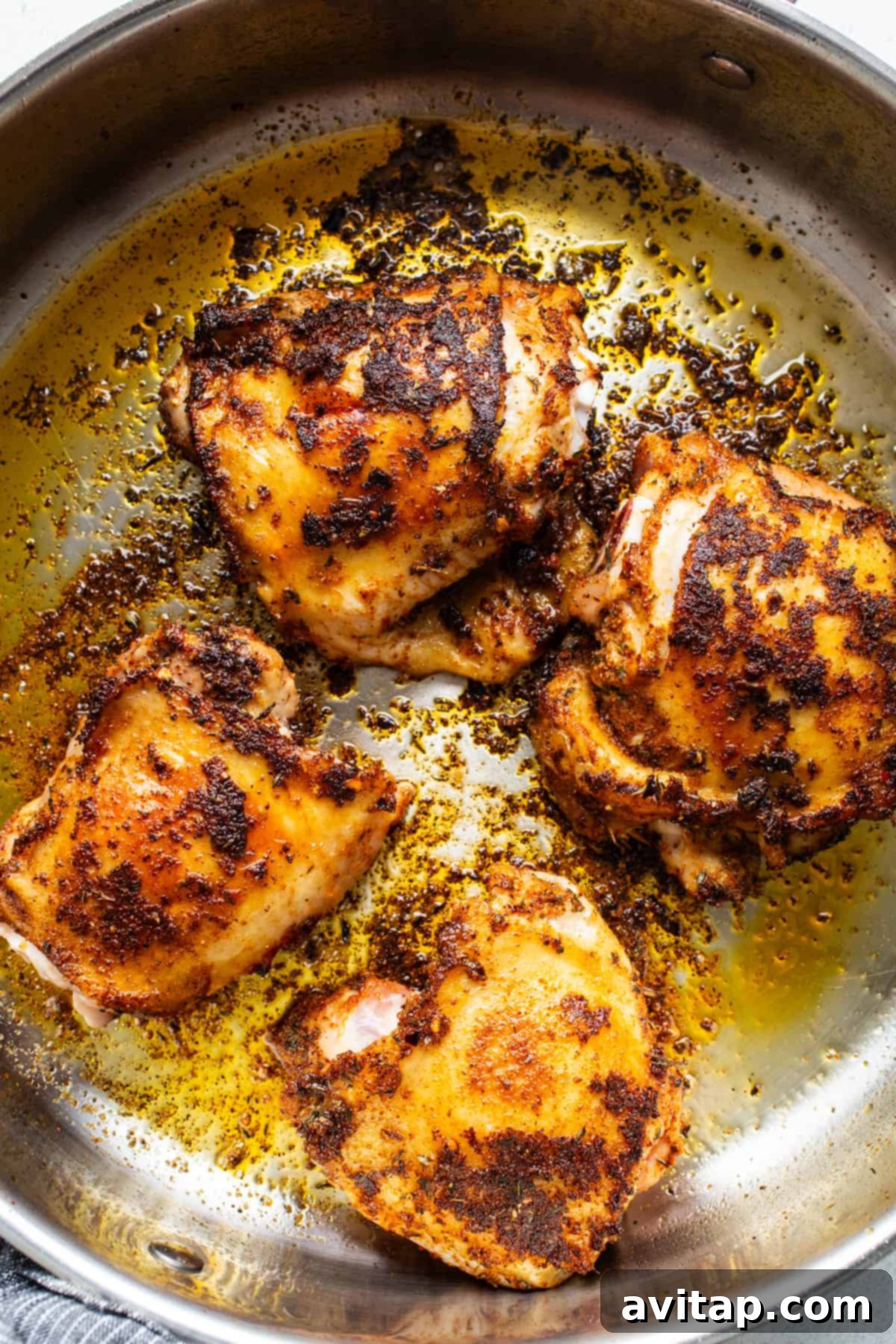 Crispy roasted chicken in a skillet on a pristine white background.