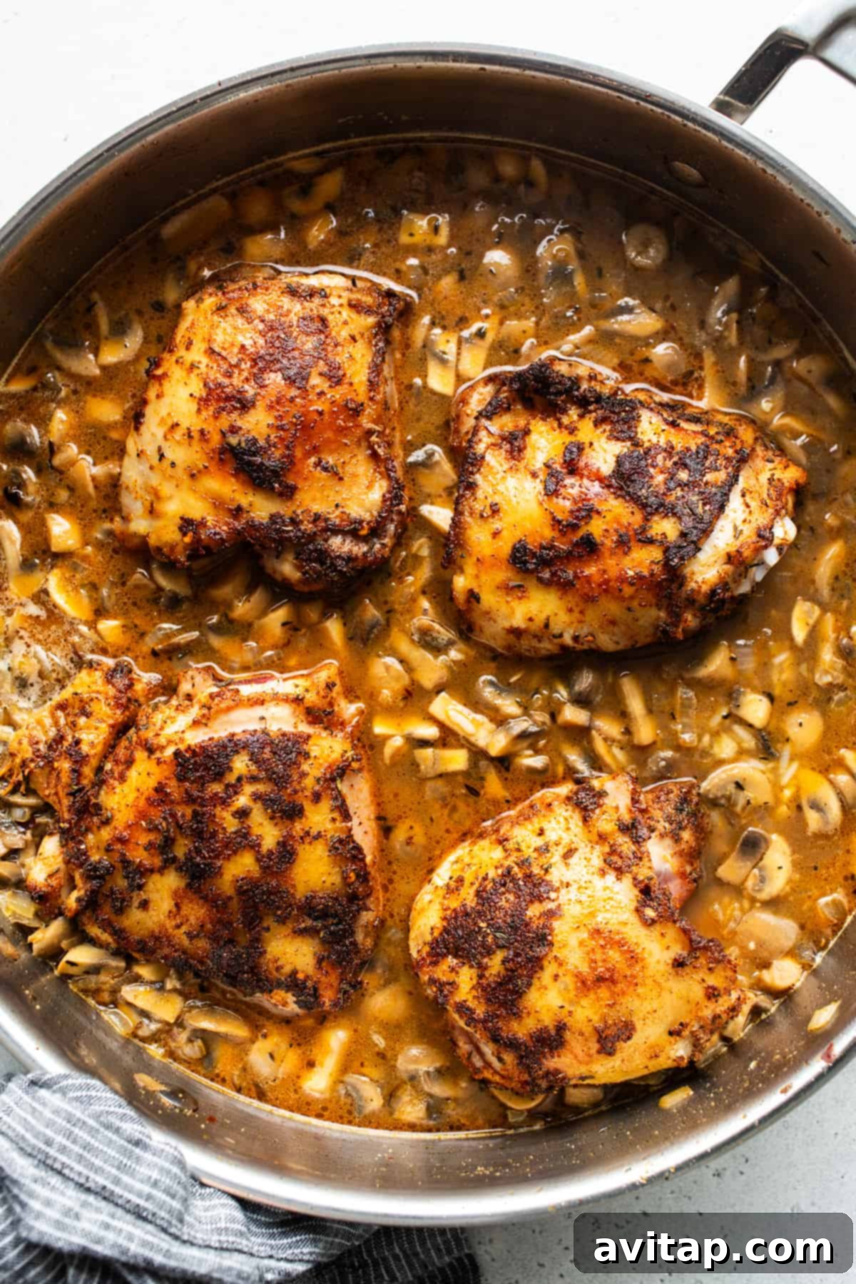 Succulent chicken breasts cooking in a pan with tender mushrooms and vibrant tomatoes.