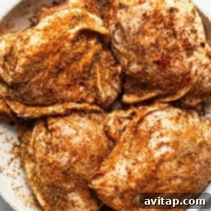 Seasoned chicken breasts on a white plate, ready for searing.