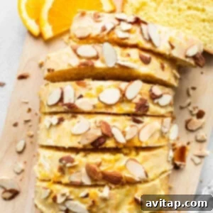 Zesty Orange Sunshine Cake 12 A freshly baked orange loaf cake, glazed and garnished with almonds, resting on a wire rack.