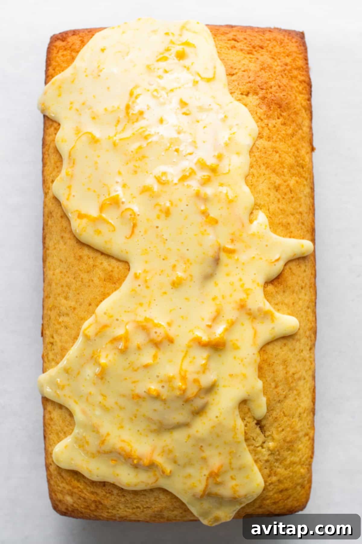 Zesty Orange Sunshine Cake 3 A thick slice of glazed orange cake on a white plate, showcasing its moist texture and golden-brown crust.