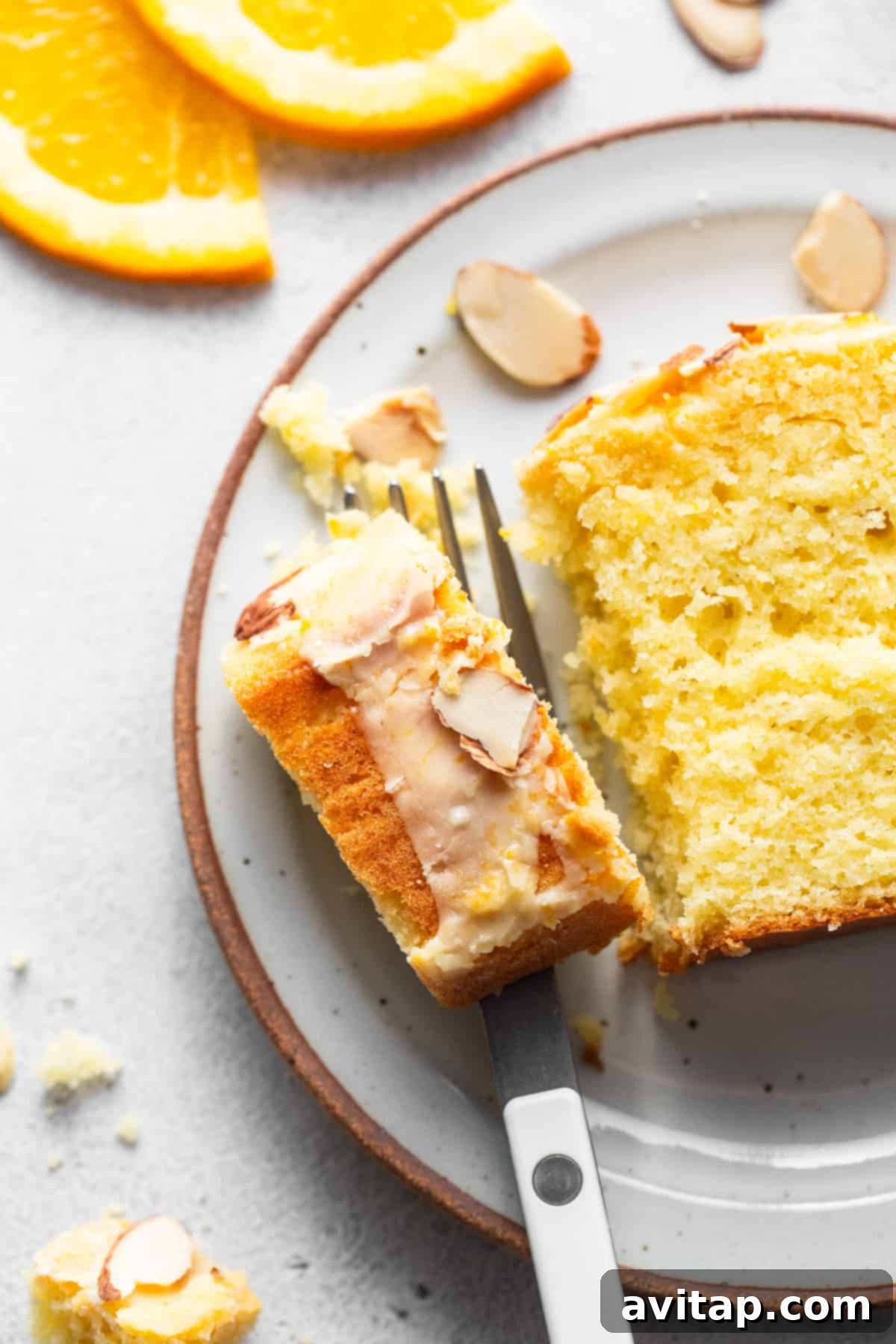 Zesty Orange Sunshine Cake 7 Two slices of orange cake with almonds on a plate, ready to be served.