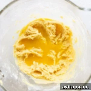 Zesty Orange Sunshine Cake 9 A glass bowl filled with thick, yellow orange cake batter, ready for baking.