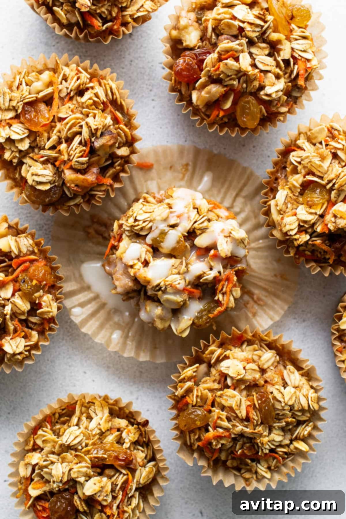 Spiced Carrot Cake Oatmeal Cups 4 A group of granola muffins on a white surface.