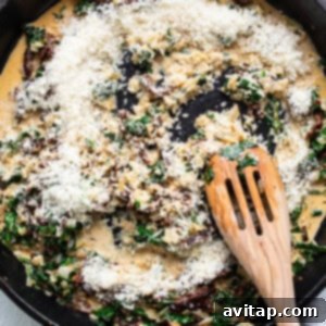 A skillet filled with spinach and cheese with a wooden spoon.