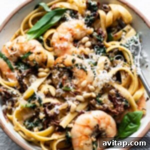 A bowl of pasta with shrimp and spinach.