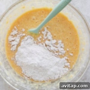 Banana Bread Ring Treats 14 A glass bowl containing a mixture of flour and a liquid batter with a green silicone spatula.