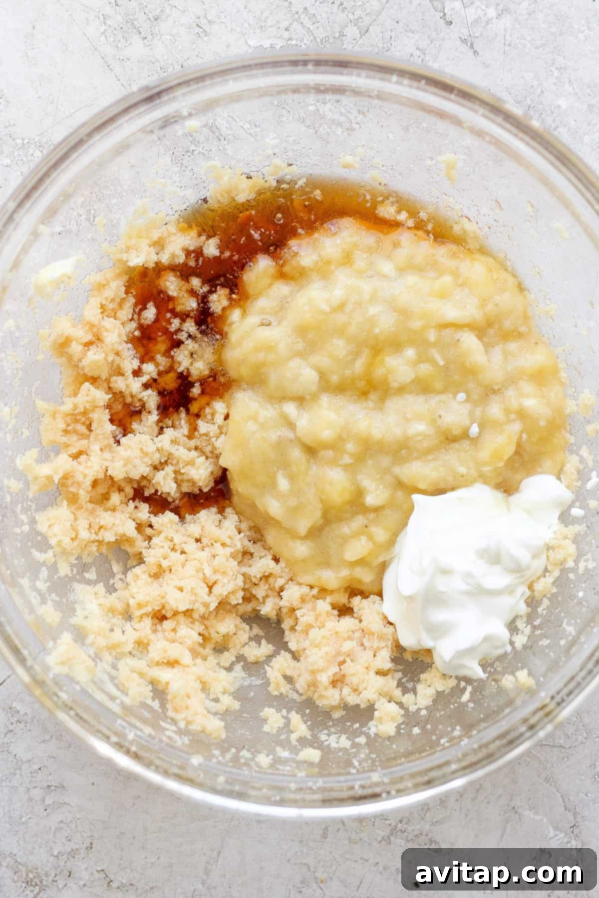 Banana Bread Ring Treats 3 Ingredients combined in a glass bowl, possibly for baking, including mashed bananas, sugars, and a dollop of sour cream or yogurt.