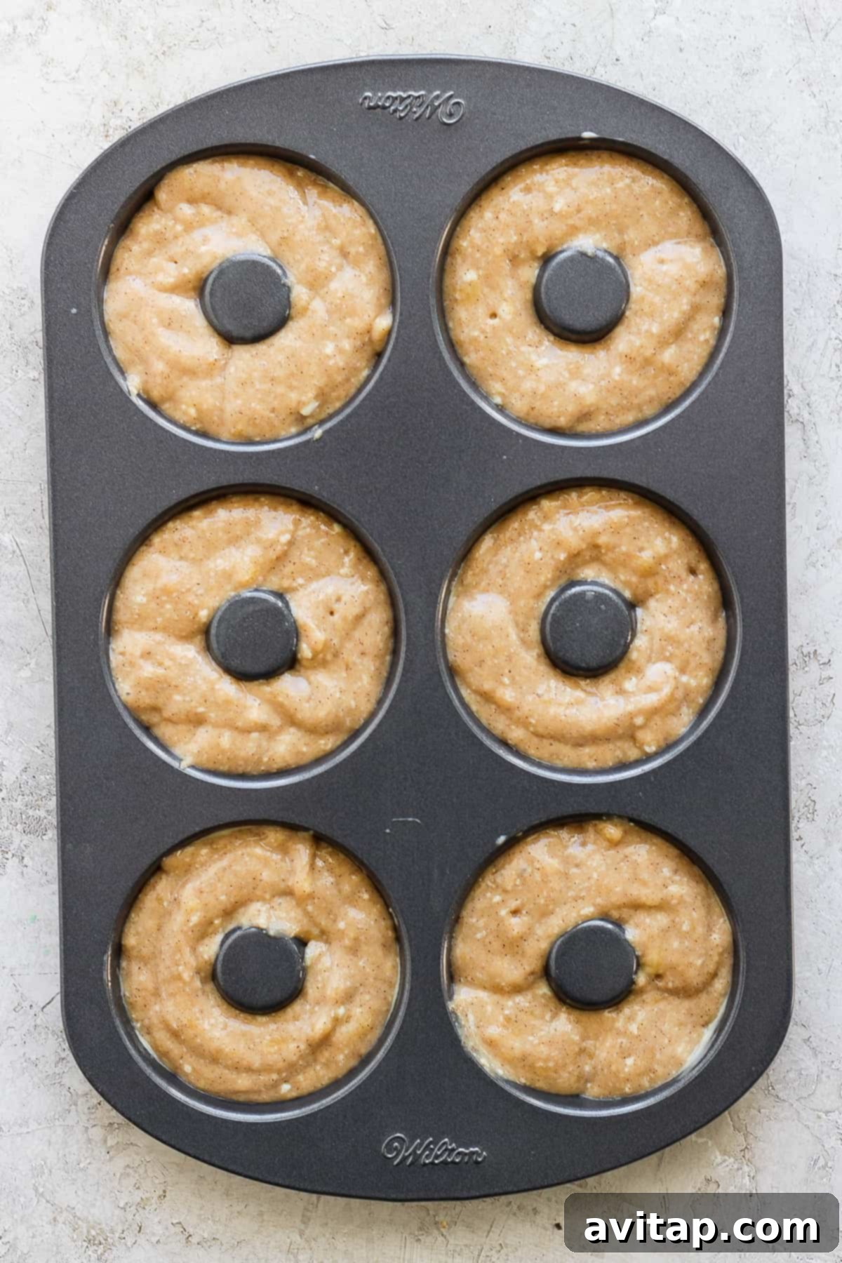 Banana Bread Ring Treats 5 A six-cavity donut baking pan filled with raw donut batter, ready to be baked.