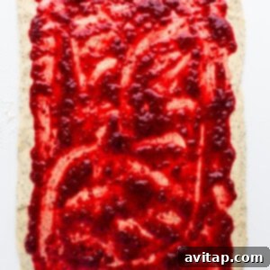 A square of dough with raspberry jam on it.