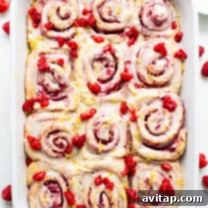 Raspberry cinnamon rolls in a white baking dish.