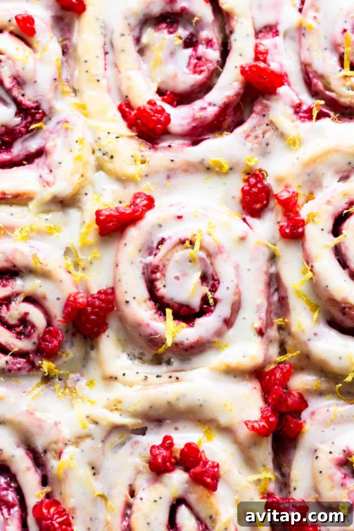 Raspberry cinnamon rolls generously drizzled with lemon icing.