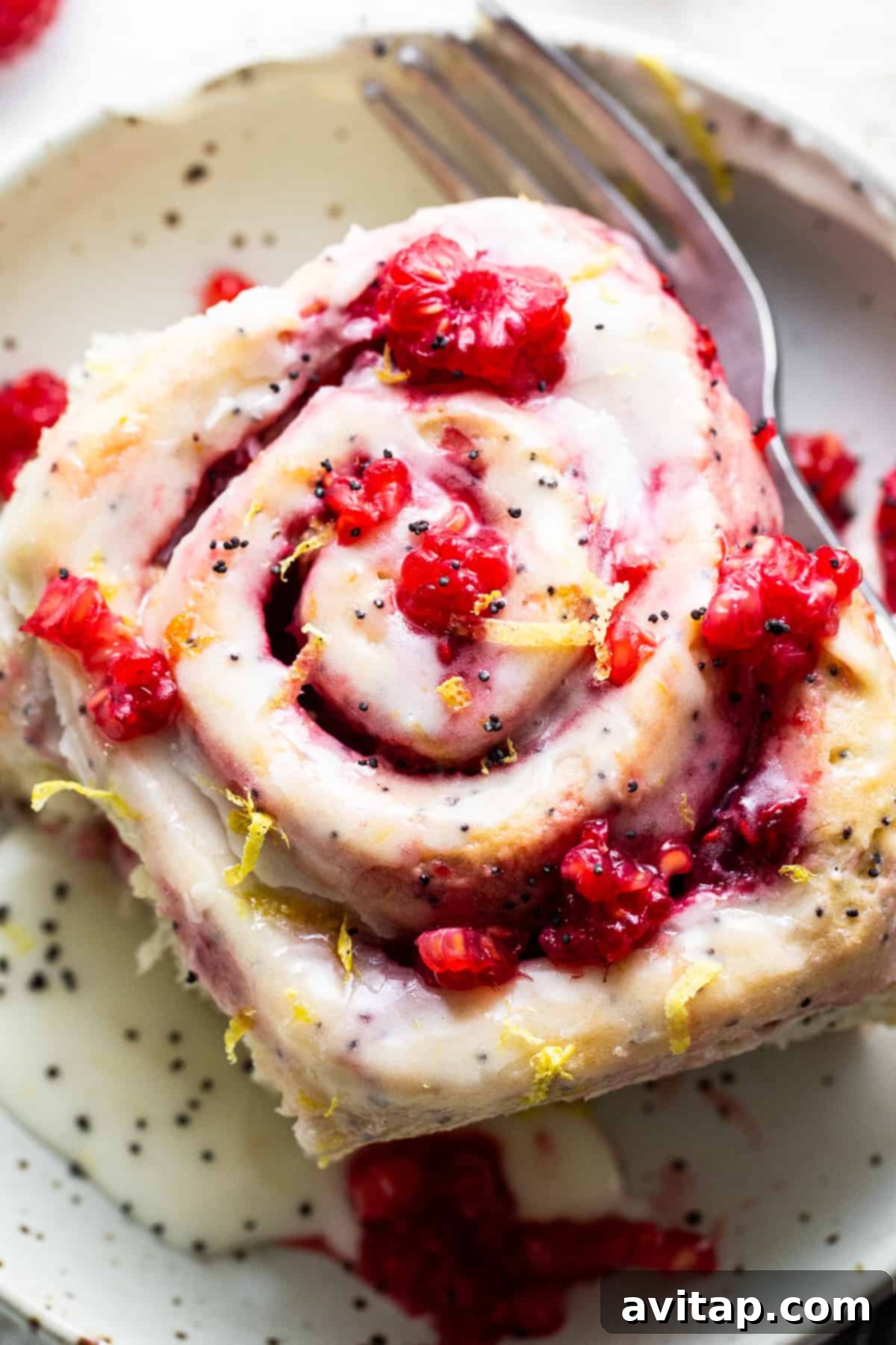 A close-up of a raspberry roll slice on a plate with a fork.