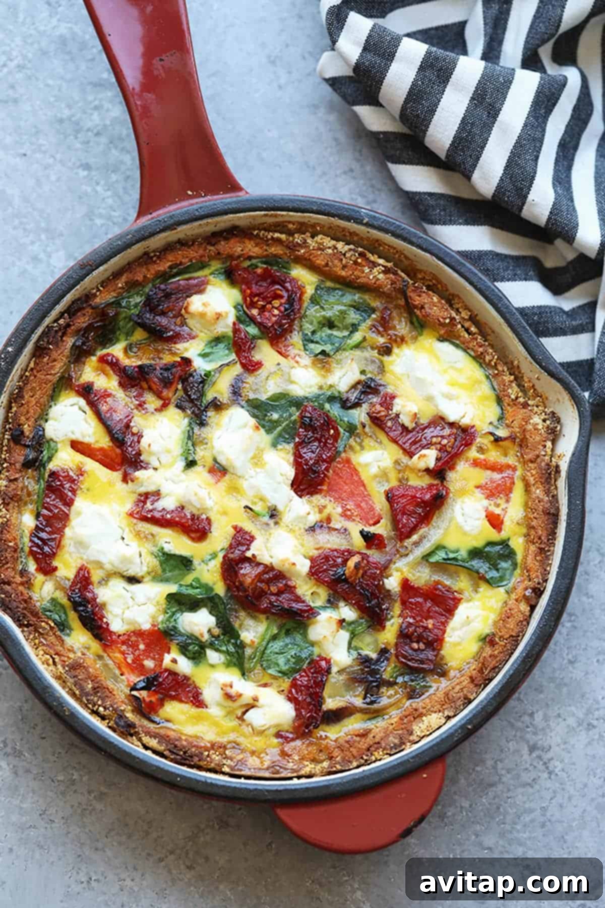 The March Wellness Culinary Club 5 A vibrant and colorful sweet potato crust quiche, adorned with fresh spinach and juicy sun-dried tomatoes, perfectly baked in a cast-iron skillet, ready to be served. This healthy and delicious homemade quiche is a star of the Fit Foodie Cooking Club.