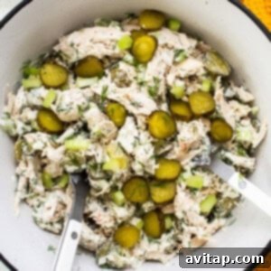 Bowl of tuna salad with pickles and herbs.