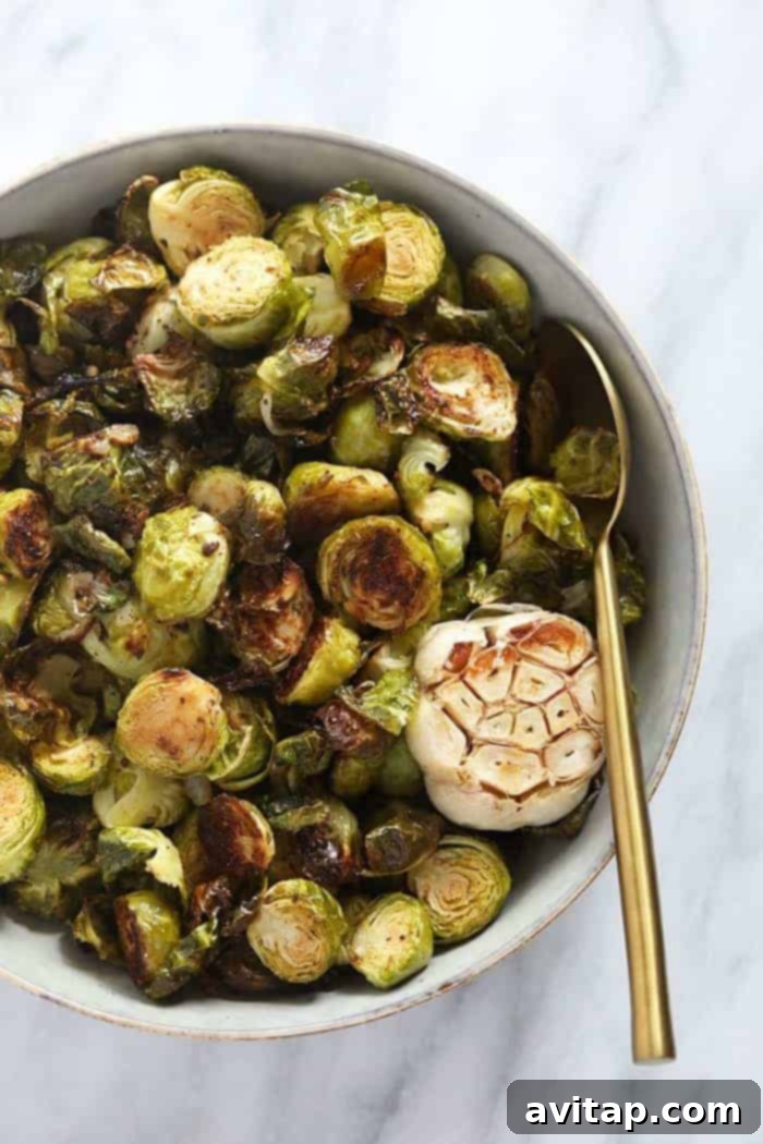 Crispy oven roasted Brussels sprouts in a rustic bowl, garnished with herbs.