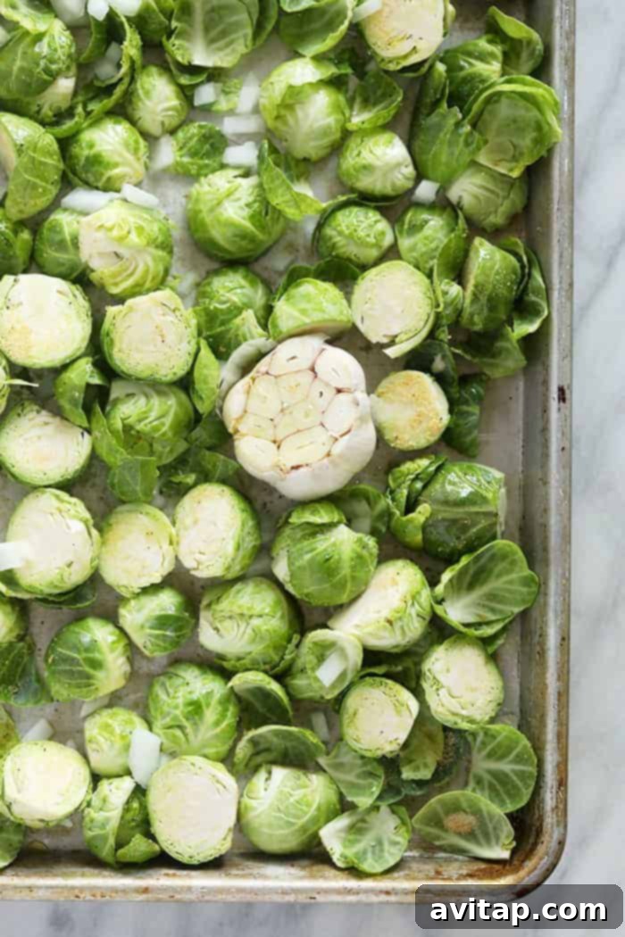 Raw, trimmed Brussels sprouts neatly arranged on a parchment-lined baking sheet, ready for seasoning.