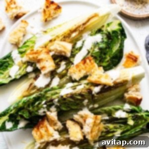 Grilled romaine lettuce with golden croutons and creamy dressing on a white plate, ready to be served.