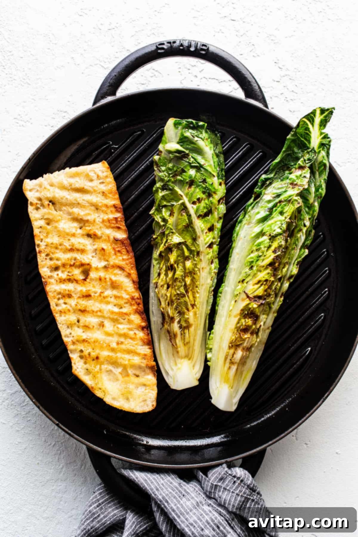 Flame-Kissed Caesar with Crispy Charred Croutons 4 Grilled fish fillet and halves of romaine lettuce cooking on a stove-top grill pan, showing appealing grill marks.