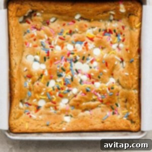 A cookie bar with sprinkles in a pan, fresh out of the oven, golden around the edges.