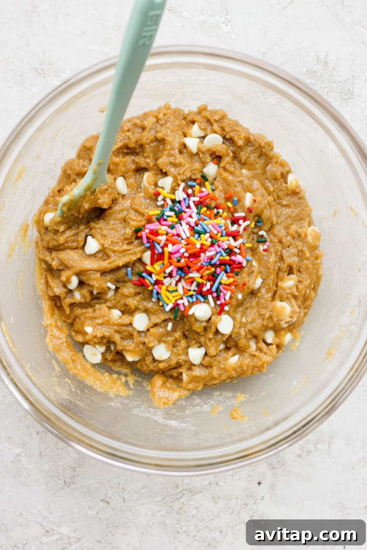 A mixing bowl filled with rich, brown blondie batter, generously studded with colorful sprinkles, ready for baking.