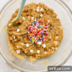 A bowl of brown dough with sprinkles, being transferred into a baking pan.