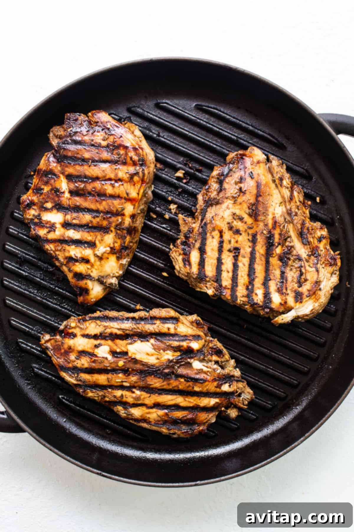 California Sunshine Grilled Chicken 3 Grilled chicken breasts in a skillet on a white background. The chicken is perfectly seared with enticing grill marks, ready for toppings.