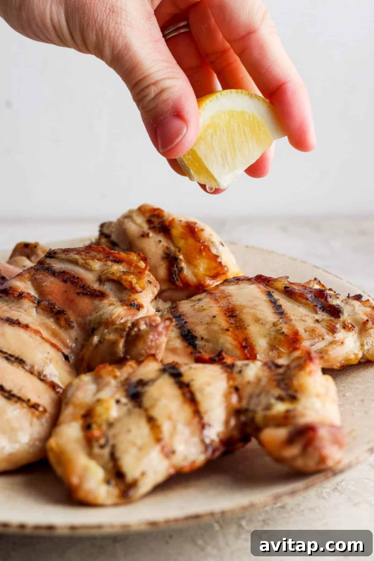 Squeezing lemon juice over grilled chicken breasts.