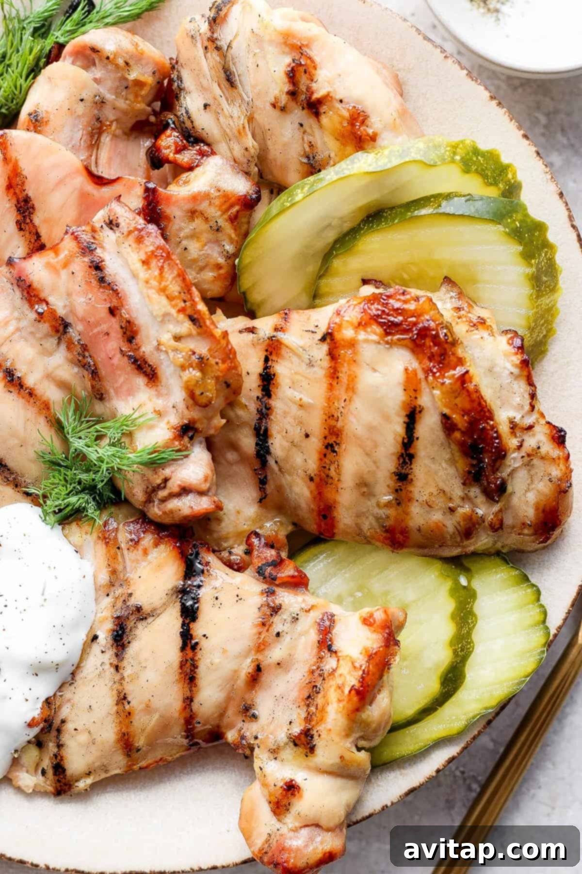Grilled chicken strips on a plate with pickles and a dollop of dipping sauce.