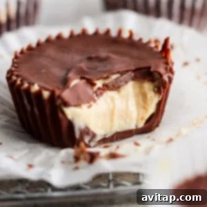 A close-up image of a chocolate peanut butter cup with a bite taken out, revealing creamy peanut butter filling. other cups in the background.
