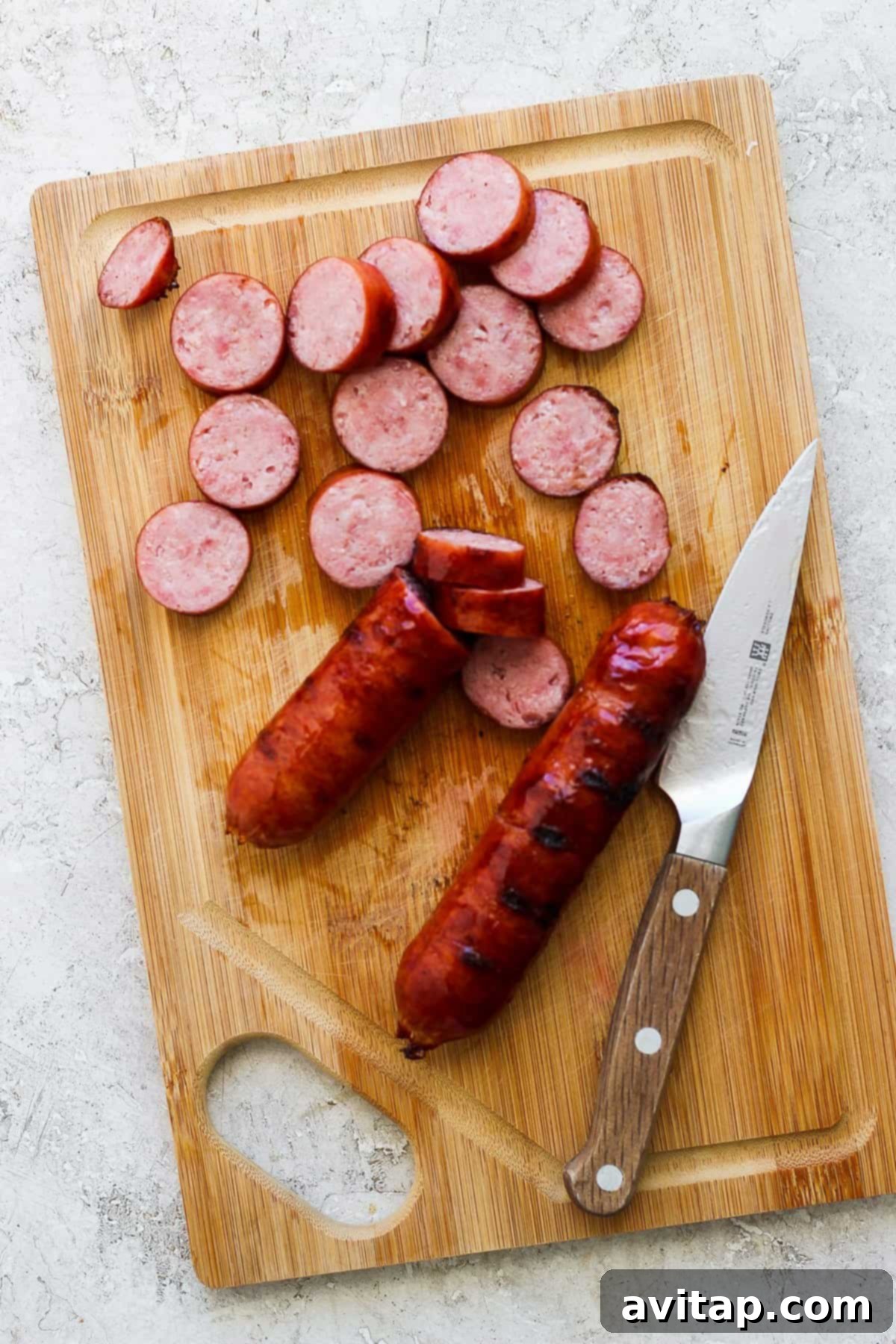 Expertly sliced savory sausage rests on a rustic wooden cutting board, accompanied by a sharp chef's knife, highlighting the preparation of quality protein for a hearty meal.