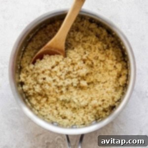 Fluffy cooked quinoa resting in a saucepan with a wooden spoon, ready to be incorporated into the protein bowls for a wholesome meal.