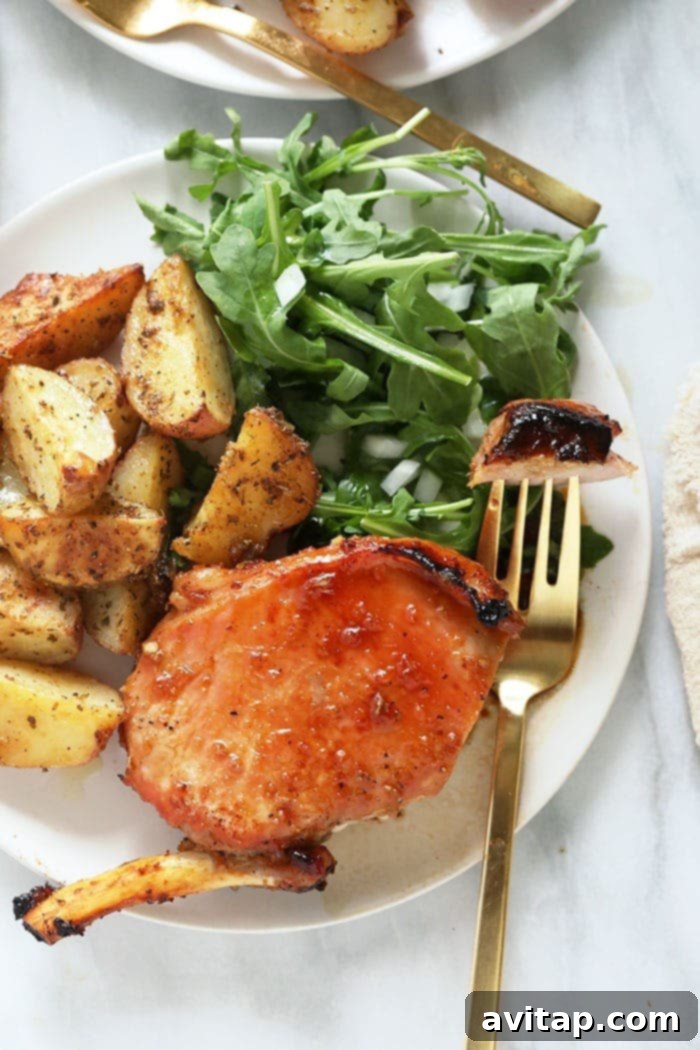 bone-in pork chops with roasted potatoes on a plate, garnished