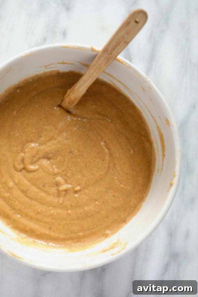 Thick, orange-hued sweet potato pancake batter in a mixing bowl, ready for cooking.