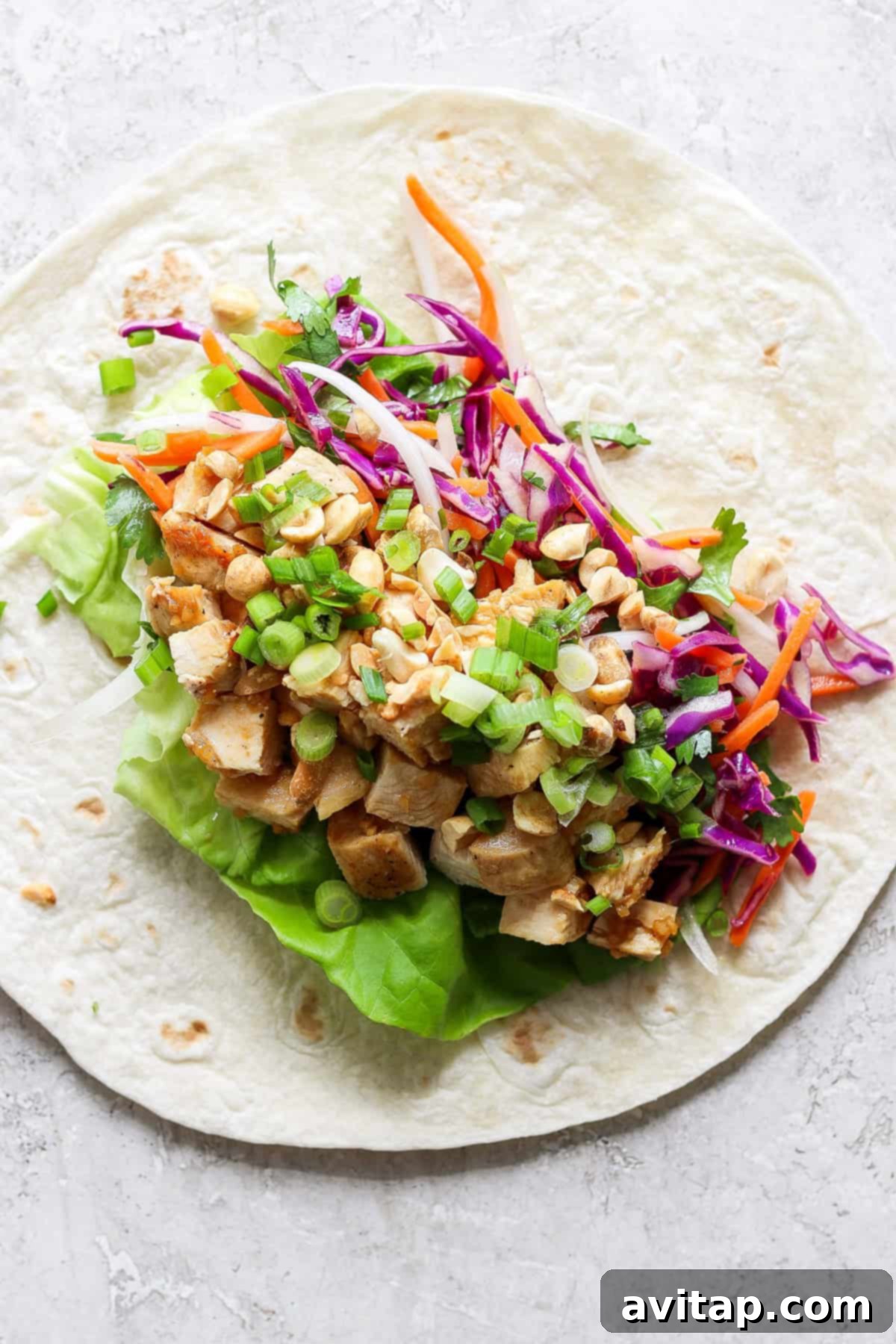 Three perfectly rolled Peanut Chicken Wraps, showcasing their vibrant filling, arranged on a light surface with a subtle background.