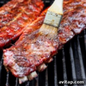 Ribs on the grill, being basted with the sticky sauce.