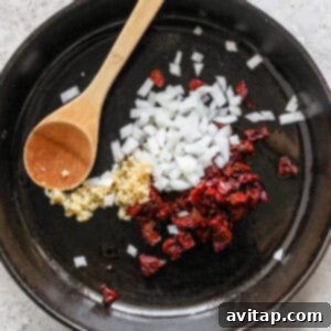 Sautéing diced onions and minced garlic in a hot skillet.