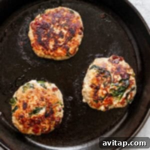 A Mediterranean burger patty searing in a hot skillet, developing a golden crust.