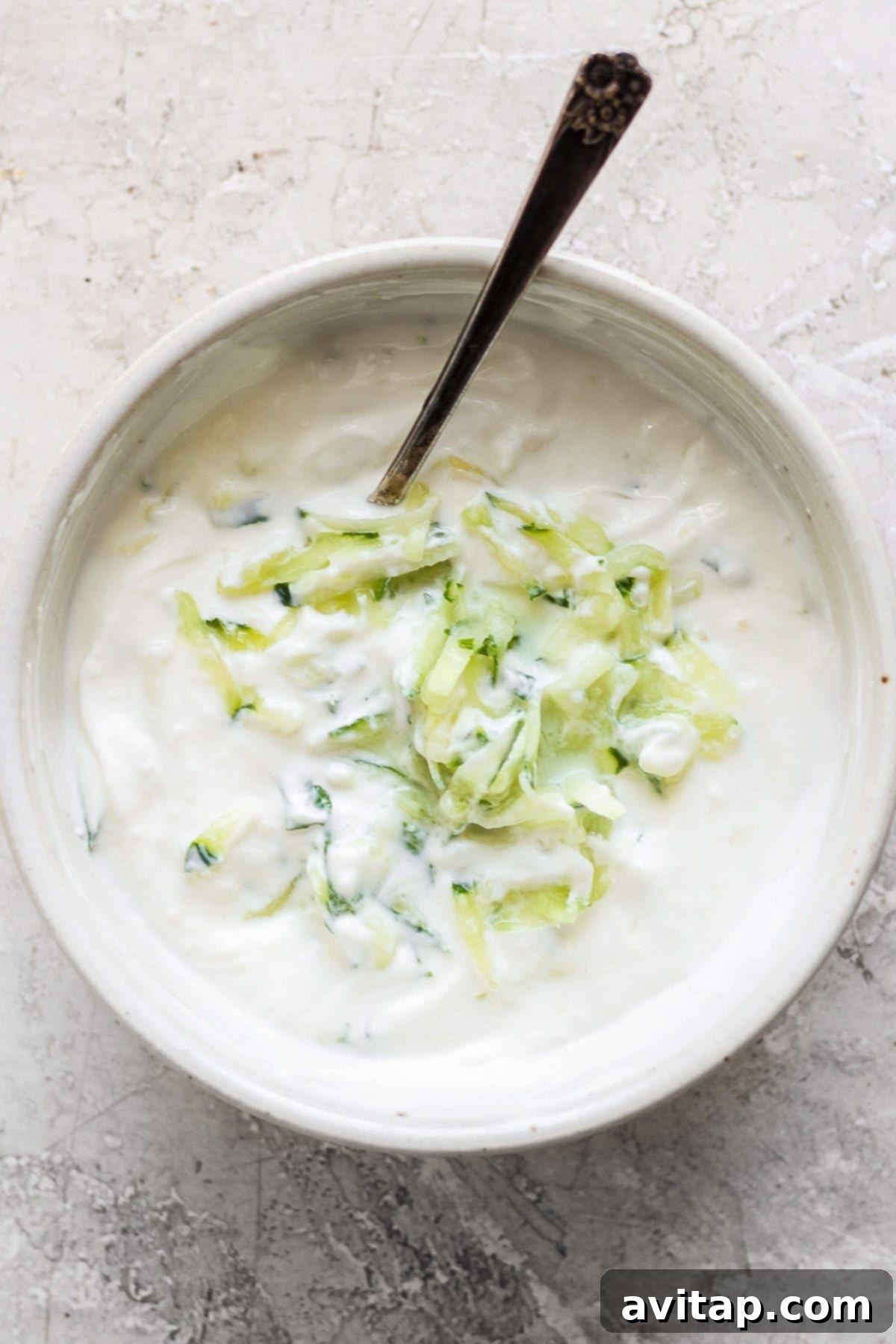 Mixing ingredients for homemade tzatziki sauce in a bowl.