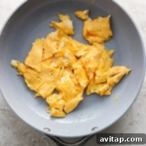 Fluffy scrambled eggs cooking in a non-stick frying pan.